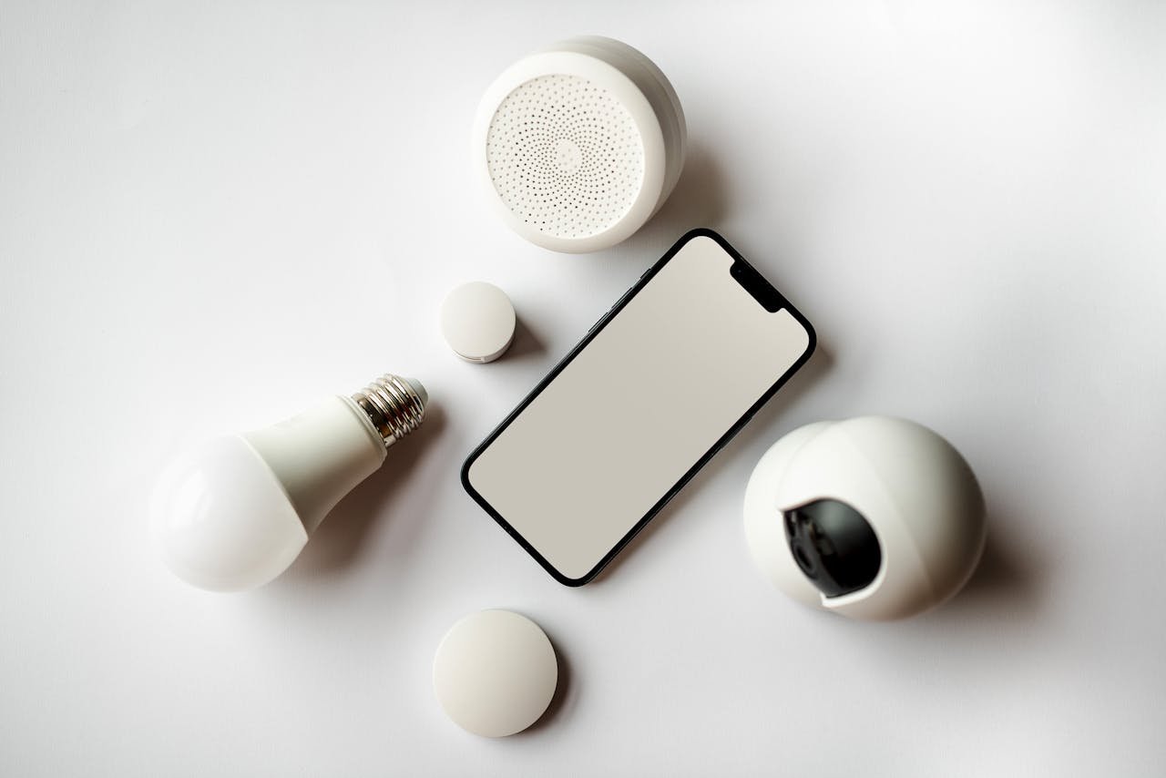 product-07 Flat lay of smartphone and smart home devices on a white backdrop, showcasing modern technology.